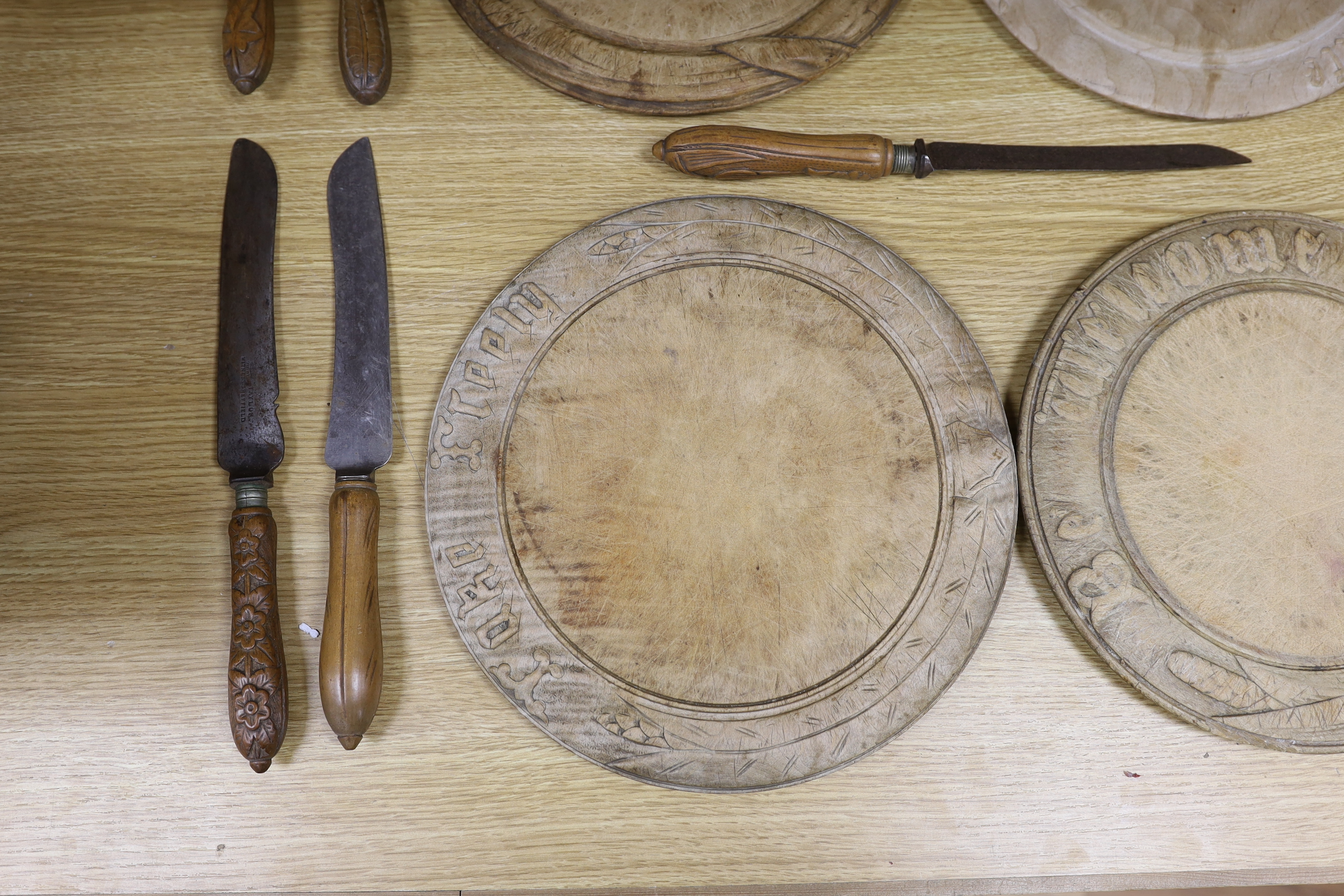 Four carved wood bread boards and a collection of knives with carved handles, boards 28cm in diameter